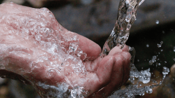 pouring water on hand - water softener vs water filter